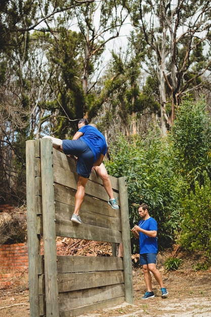 Entraîneur féminin aidant l'homme à escalader un mur en bois