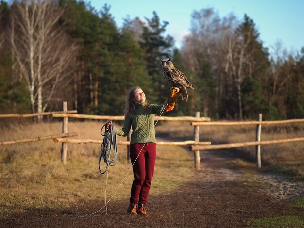 Entraîneur de fille tient un hibou sur sa main.