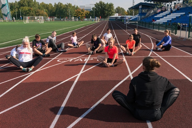 Photo entraîneur et groupe d'enfants organise une session de formation à l'école du stade gym trainings o