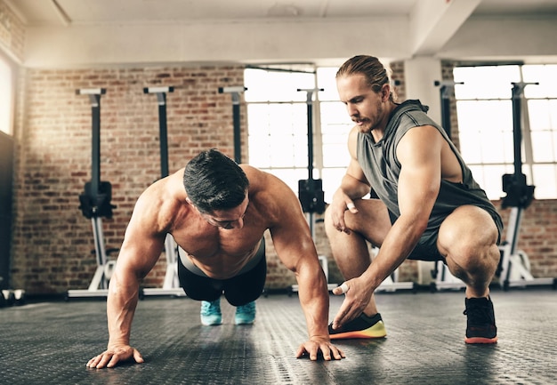 Entraîneur d'homme et motivation pour les pompes sur le sol du gymnase pour la santé de la forme physique et la construction musculaire pour le sport Entraîneur personnel bodybuilder hommes et entraînement avec des conseils aidant la main et ensemble pour le soutien