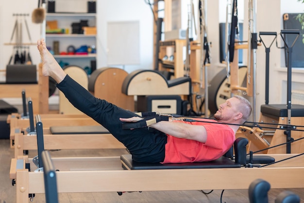 L'entraîneur masculin de pilates de forme physique montre des exercices dessus