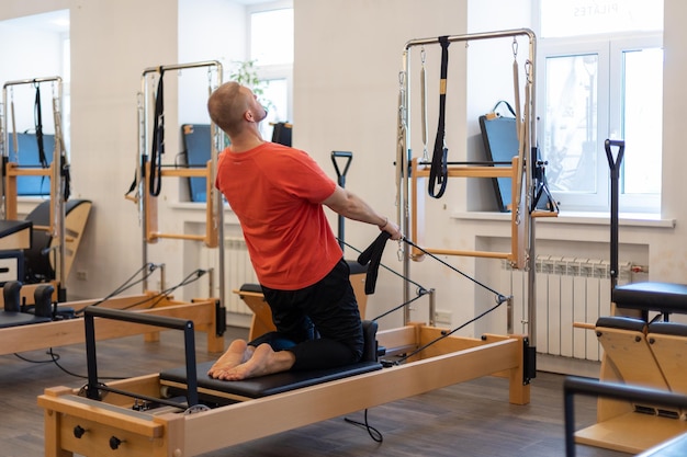 L'entraîneur masculin de pilates de forme physique montre des exercices dessus