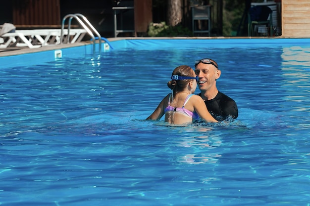 L'entraîneur de natation donne une leçon individuelle avec une fillette de 8 ans dans l'eau de la piscine