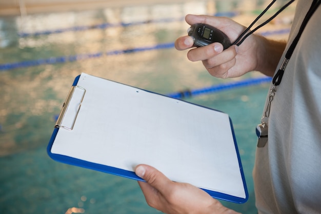 Entraîneur de natation en regardant son chronomètre de la piscine