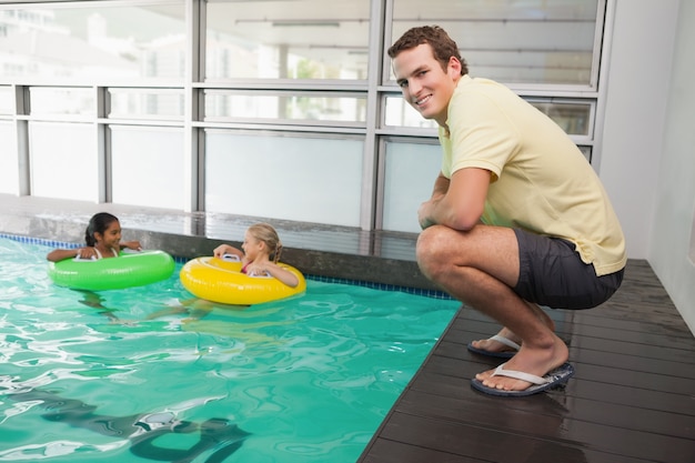 Entraîneur de natation souriant à la caméra au bord de la piscine