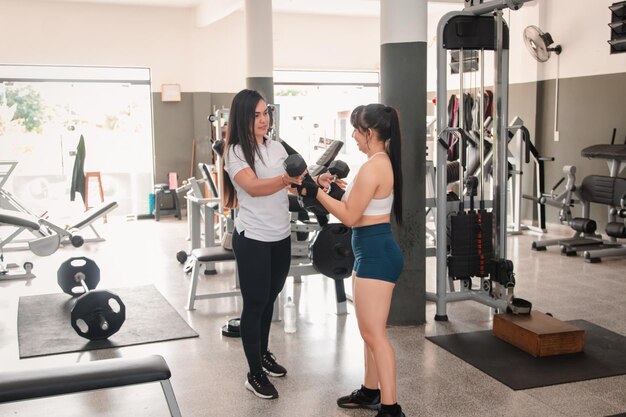 Entraîneur passant des haltères à une fille de fitness dans la salle de sport