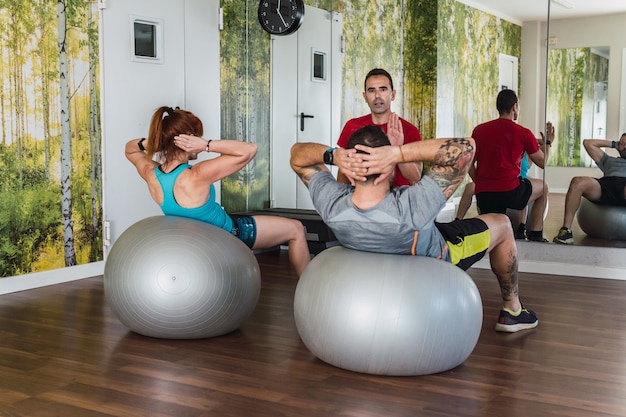 Entraîneur Personnel Expliquant Les Exercices De Pilates à Un Groupe De Personnes Dans Une Salle De Sport.