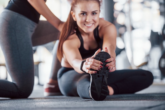 Entraîneur personnel féminin aidant une femme à faire des exercices dans la salle de gym.