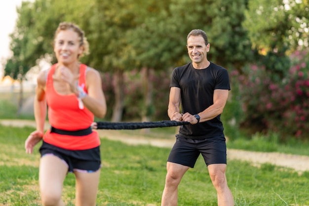 Entraîneur personnel masculin s'exerçant avec une femme et l'aidant avec l'entraînement.