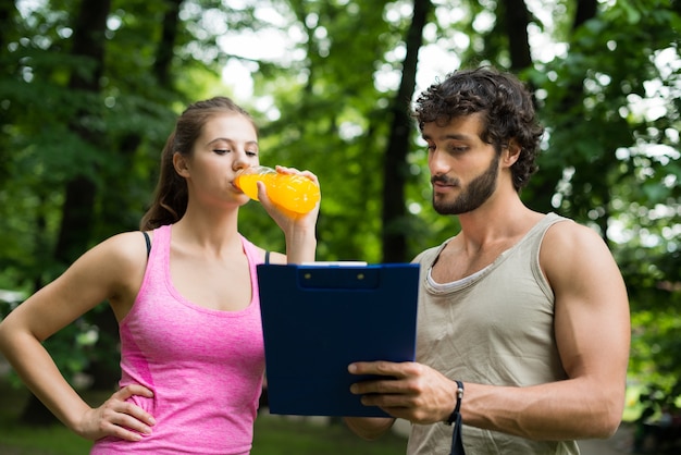 Entraîneur personnel montrant une table d&#39;entraînement à une femme