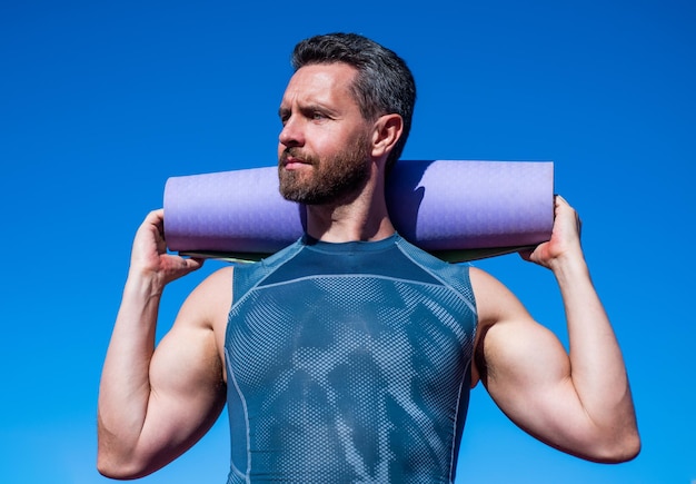 entraîneur de pilates avec tapis de yoga sur fond de ciel, sport.