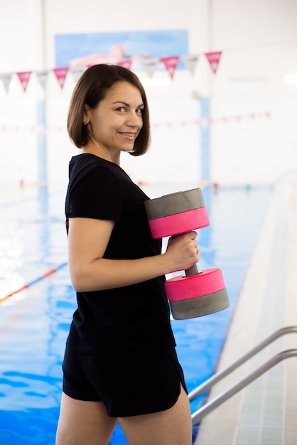 Un entraîneur près de la piscine sportive s'entraîne à l'aquagym.