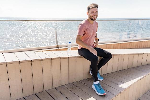 L'entraîneur se repose, s'entraîne avec des vêtements de sport, se réchauffe, un coureur souriant.