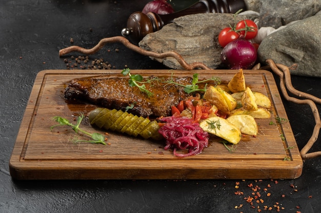 Entrecôte avec pommes de terre. plat de viande avec bœuf, pommes de terre au four et apéritifs de légumes marinés