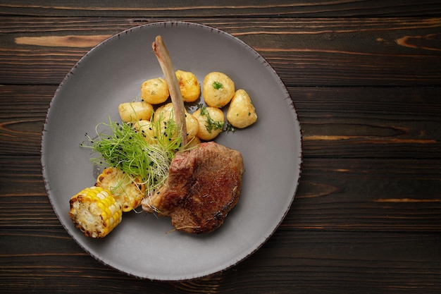 Entrecôte de veau aux pommes de terre et maïs sur fond de bois