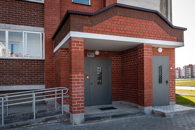 Entrée d'un immeuble d'habitation avec porte métallique avec interphone.