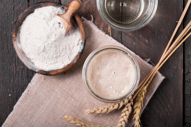 Entrée de levain pétillant fait maison frais, un mélange fermenté d'eau et de farine à utiliser comme levain pour la cuisson du pain sur une table en bois