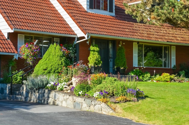 Entrée de la maison familiale avec toit en tuiles et cour avant délicatement paysagée