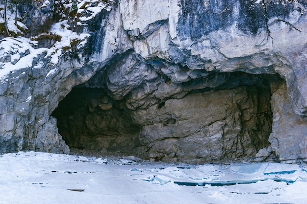 Entrée sombre de la grotte Vue d'une grotte sombre au bord d'un lac glacé