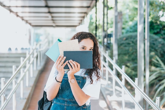 Entrée à l'université Portrait d'une belle fille arabe intelligente tenant des livres de texte d'étude souriant en regardant la caméra. L'étudiant authentique a beaucoup à étudier et à lire, pour les devoirs de classe, la préparation aux examens