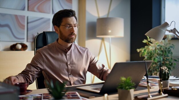 Photo entrepreneur à l'écran d'un ordinateur portable travaillant au bureau de près homme buvant du café