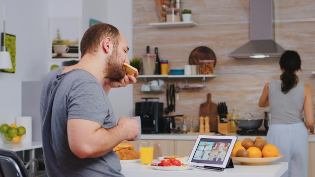 Entrepreneur lors d'une vidéoconférence en prenant son petit-déjeuner dans la cuisine. Indépendant travaillant à distance, parlant en vidéoconférence, appel vidéo en ligne, réunion Internet depuis la maison, appareil de communication