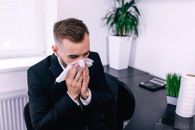 Entrepreneur malade soufflant dans une lingette au bureau se sentant malade et t