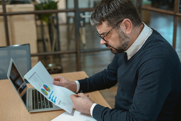 Photo entrepreneur masculin sérieux travaillant seul au bureau