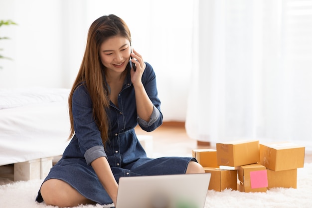 Entrepreneur PME de jeunes femmes asiatiques travaillant avec un ordinateur portable pour les achats en ligne à domicile et parler avec le client à l'ordre de livraison