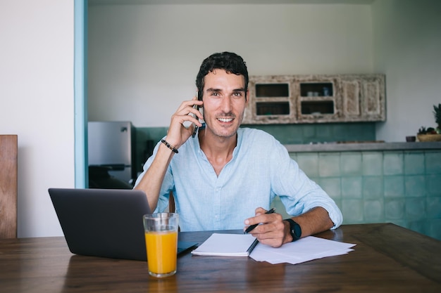 Entrepreneur souriant à la recherche de têtes avec un smartphone à la maison