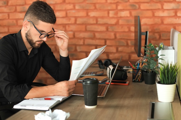 L'entrepreneur à succès étudie les documents avec un regard attentif et concentré.