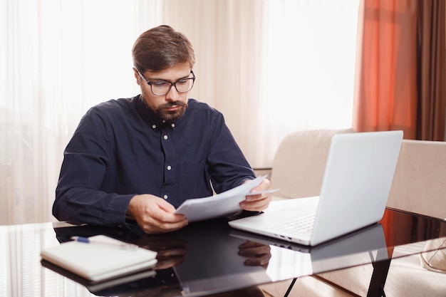 L'entrepreneur travaille avec un ordinateur portable et conserve un document dans un bureau à domicile