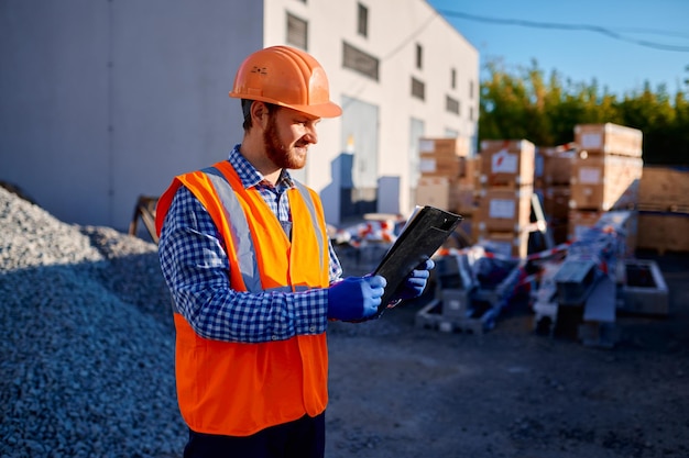 Entrepreneur vérifiant l'examen du colis livré avec des matériaux de construction sur le chantier de construction