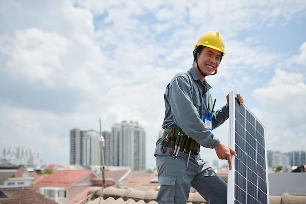 Entrepreneur vietnamien positif debout sur le toit avec panneau solaire