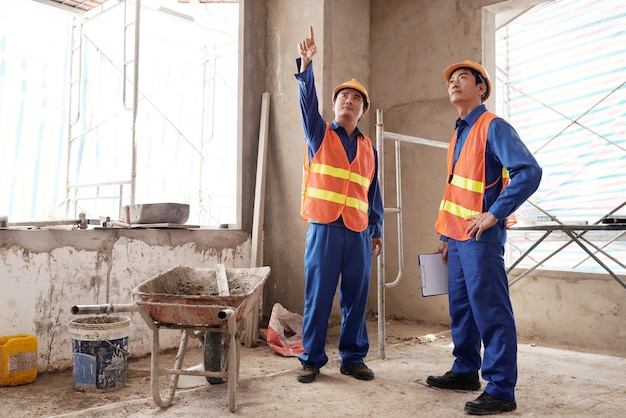 Entrepreneurs discutant des travaux qui doivent être effectués dans une maison en cours de rénovation