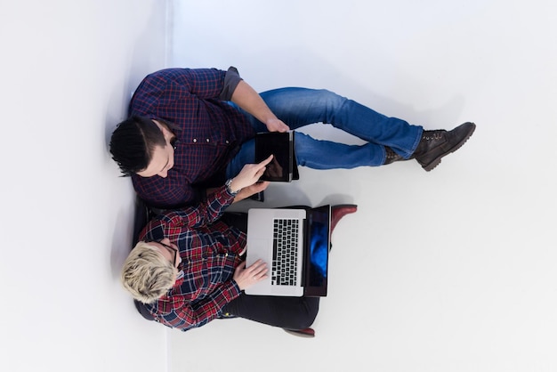 entreprise de démarrage et nouveau concept de technologie mobile avec un jeune couple dans un intérieur de bureau moderne et lumineux travaillant sur un ordinateur portable et une tablette sur un nouveau projet créatif et un remue-méninges, vue aérienne de dessus