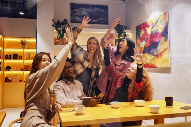 Une entreprise de jeunes dans un café s'amuse à boire du café s'amuse à naviguer sur les réseaux sociaux avec ac