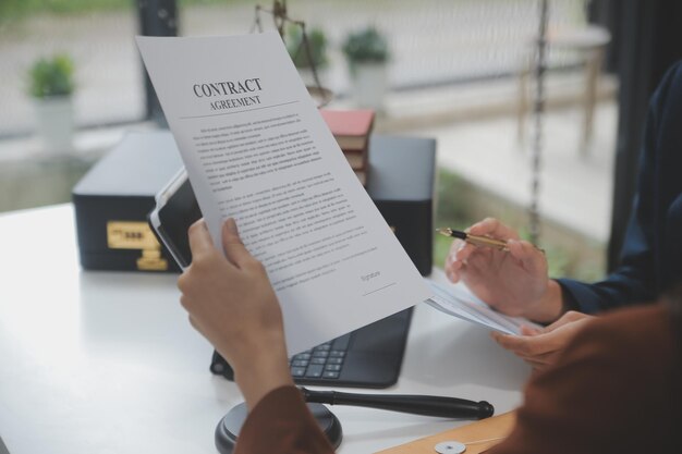 Les entreprises et les avocats discutent des documents contractuels avec une échelle en laiton sur le bureau du bureau Les services juridiques Conseil de la justice et du droit Image conceptuelle avec effet de grain de film