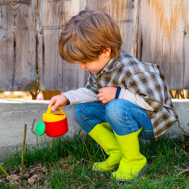 Entretien et arrosage des fleurs Devenir petit agriculteur Heureux petit agriculteur s'amusant sur le terrain Printemps ou été pour les enfants du ranch