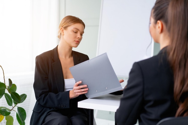 Entretien d'embauche Concept de carrière et de placement dans les affaires Jeune femme blonde tenant un CV assis devant le candidat lors d'une réunion d'entreprise ou d'un entretien d'embauche