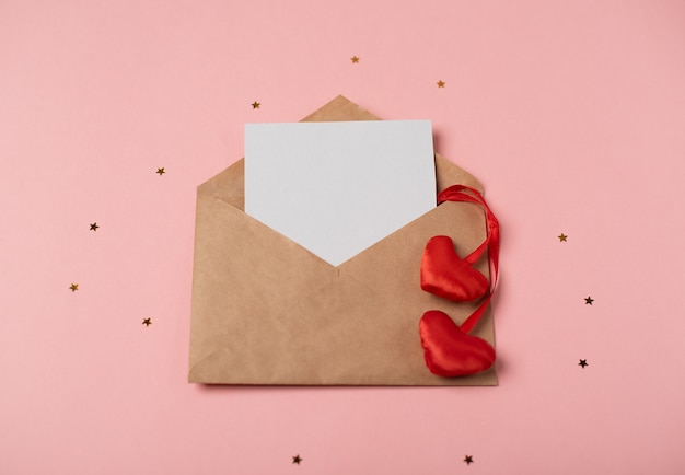 Enveloppe artisanale avec une feuille de papier vierge et les coeurs rouges. Concept de la Saint-Valentin.