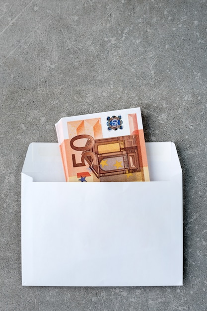 Enveloppe blanche avec billets de 50 euros.