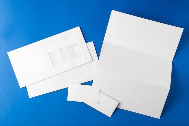 Photo enveloppe blanche de brochure et carte sur fond bleu