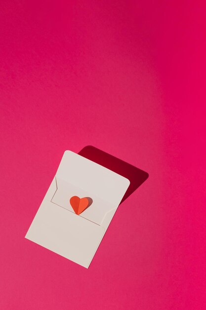 Enveloppe blanche avec coeur rouge sur fond rose magenta Concept minimal d'amour ou de la Saint-Valentin