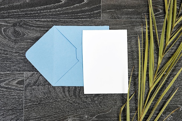 enveloppe bleue avec papier blanc avec feuille de palmier verte sur bois feuille de papier blanc sur un tex en bois foncé