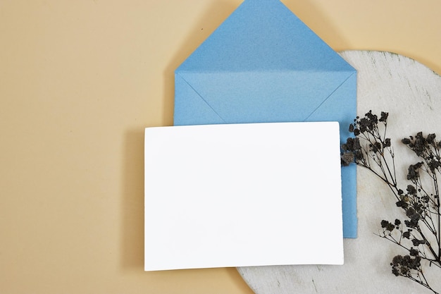 enveloppe bleue avec papier blanc et fleurs de gypsophile noires au-dessus du podium en marbre feuille de papier blanc