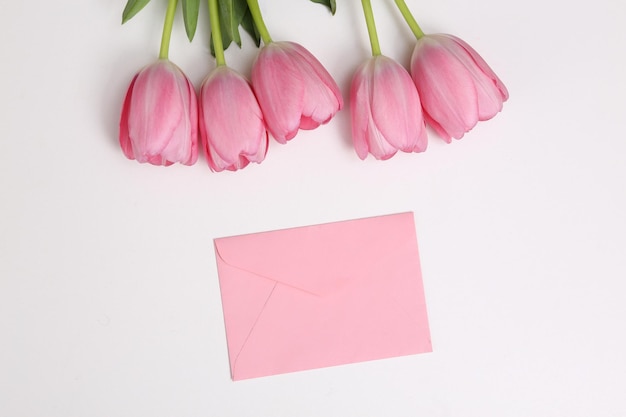 Enveloppe et bouquet de tulipes roses sur fond blanc Vue de dessus