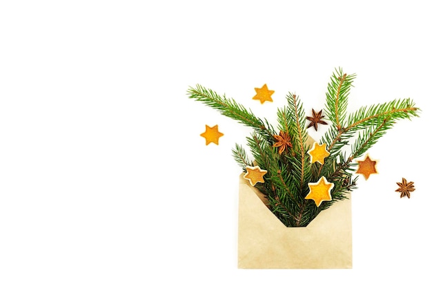 Une enveloppe avec des branches de sapin des étoiles d'écorce d'orange et des étoiles d'anis sur fond clair