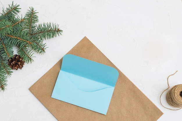 enveloppe cadeau en papier kraft sur fond de lettre de branches de sapin et enveloppe à la main pour Noël.