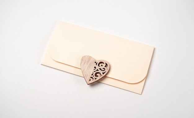 Une enveloppe et un coeur en bois dessus sur blanc. Lettre d'amour pour le concept de la Saint-Valentin.